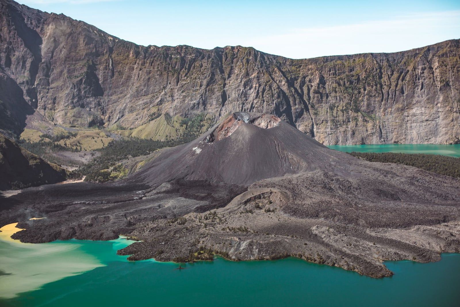 Turquoise waters of Segara Anak crater lake surround the volcanic cone of Mount Barujari inside Mount Rinjani's caldera.